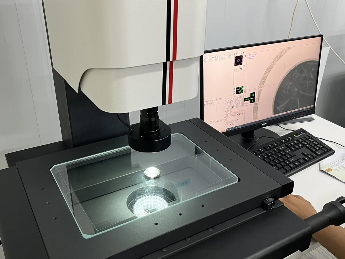 Vision measuring system checking a part profile on a lit glass stage in the QC room