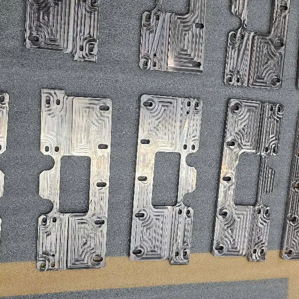 Rows of CNC milled plates with narrow channels, centre window and counterbored holes