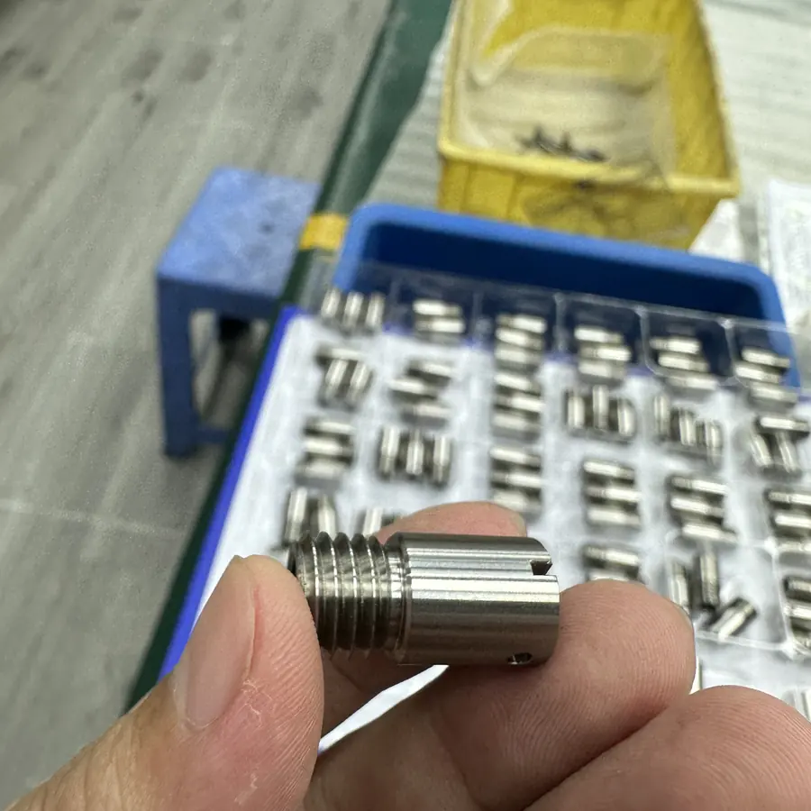 CNC turned threaded bushing with slotted end and cross hole, batch in inspection tray